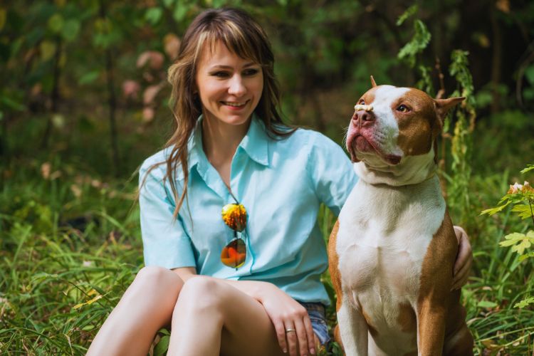 cachorro pitbull e mulher juntos no jardim